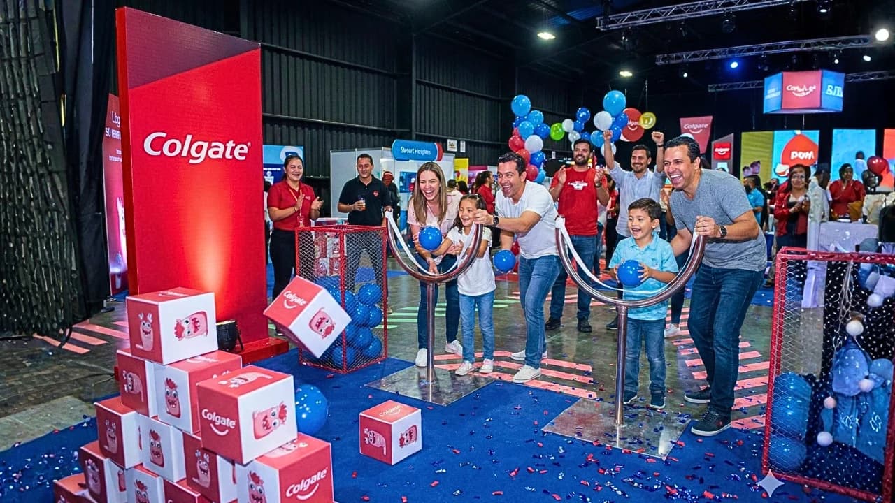 Evento Colgate con escenario de marca, participantes, globos y confeti